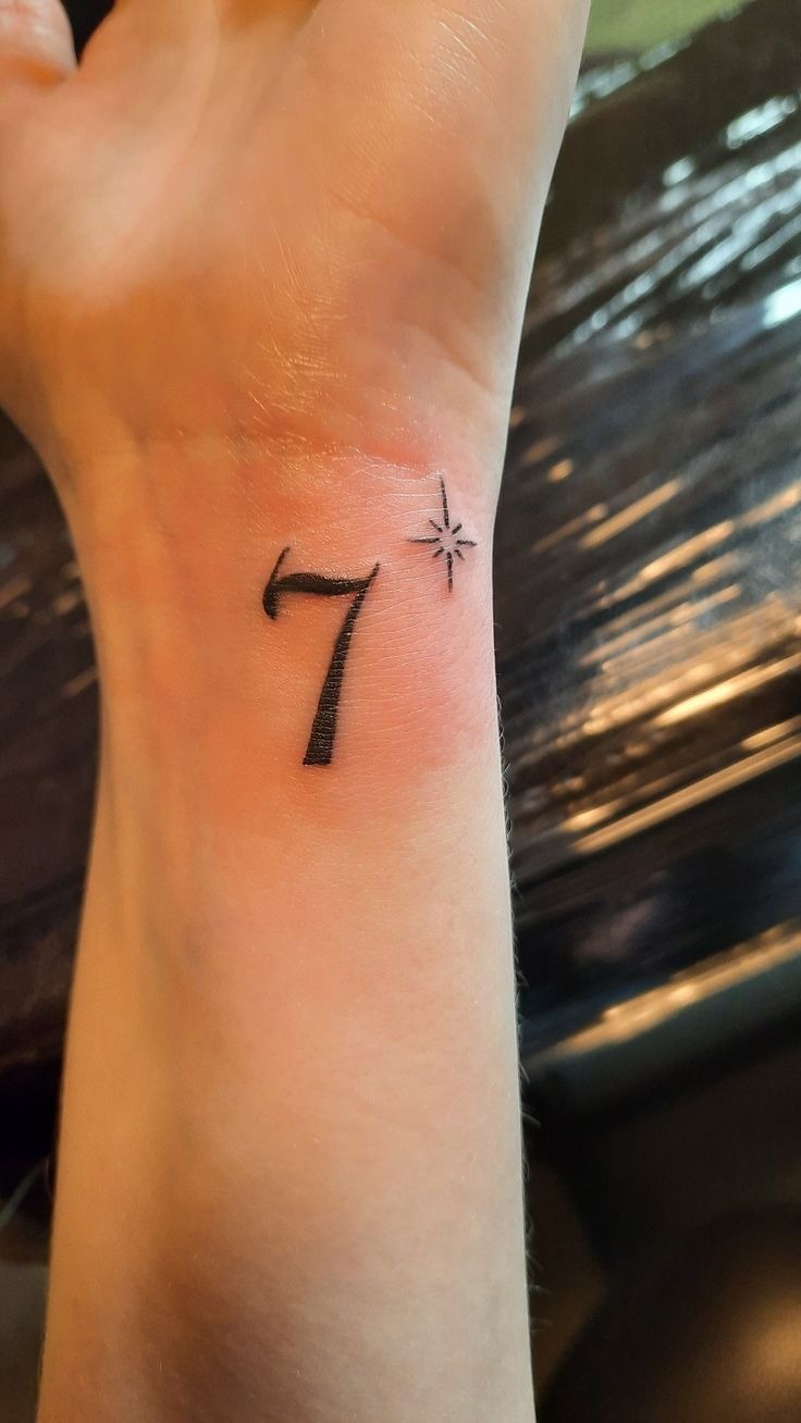 Single 7 Wrist Tattoo with Sparkle, a tattoo design rendered in delicate fine-line.