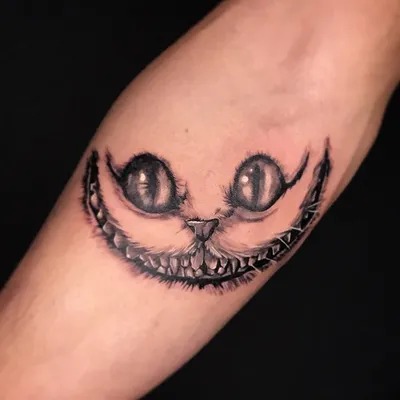 One of the most recognizable designs is a black and white Cheshire Cat tattoo featuring only its signature grin and wide, mischievous eyes.