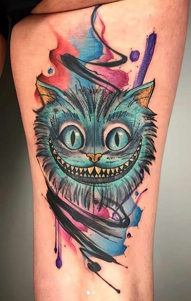 This tattoo uses a striking watercolor style with bold blues and purples to emphasize the Cheshire Cat's floating head.