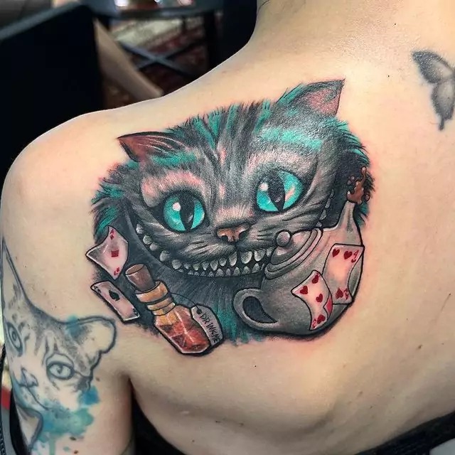 This tattoo design brings a touch of color and whimsy to the classic Cheshire Cat.