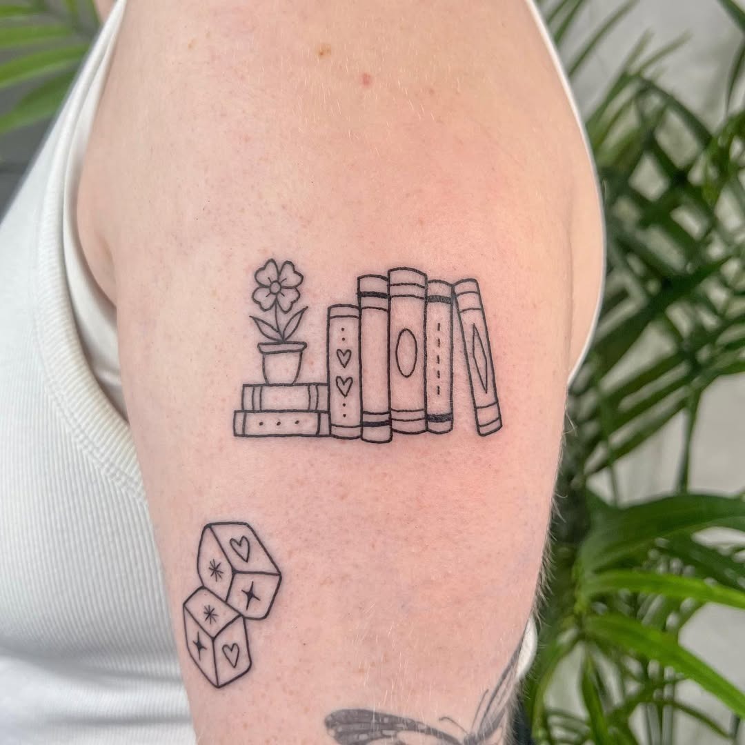 This tattoo features a cute stack of books with a flower on top, embodying a love for literature.