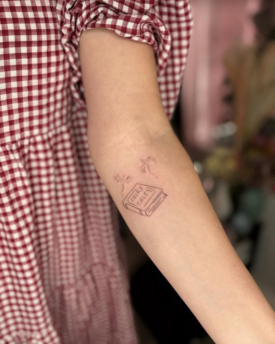 This tattoo features a delicate book illustration with whimsical elements, creating a serene vibe.