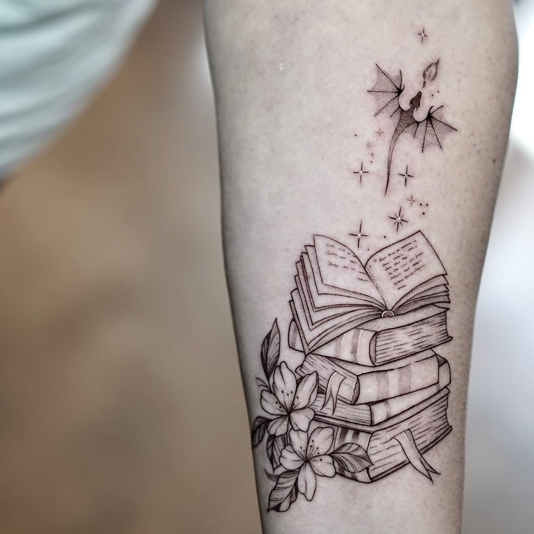 This tattoo features a beautifully detailed stack of books, intertwined with delicate flowers and starry elements.