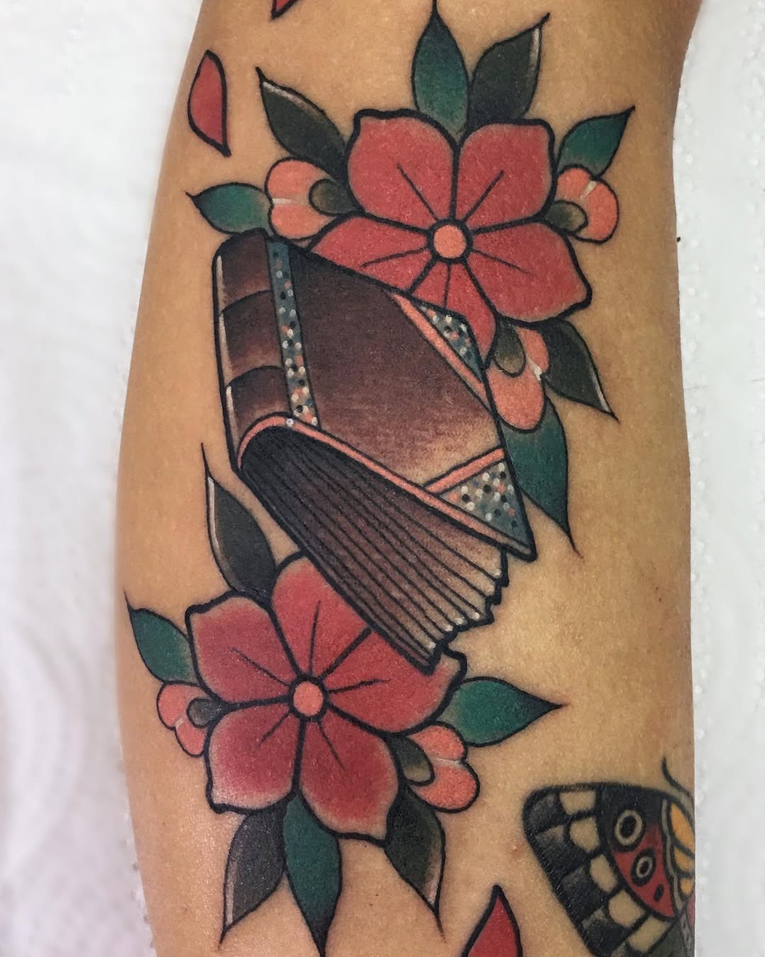 This tattoo showcases a beautifully detailed book, adorned with elegant floral motifs.