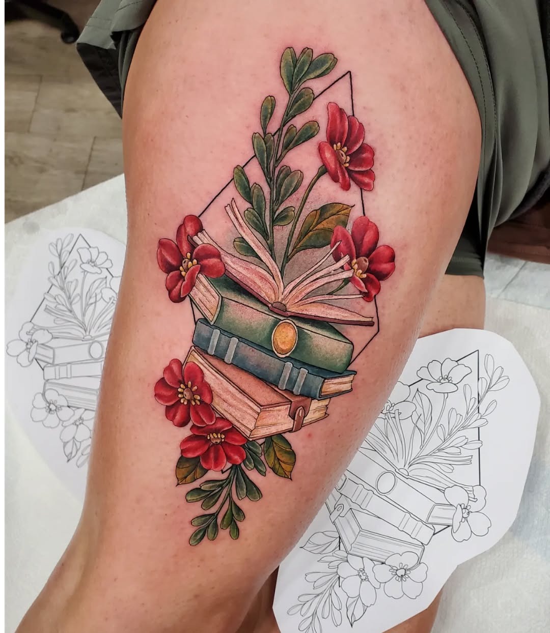 This tattoo showcases beautifully stacked books adorned with red flowers.