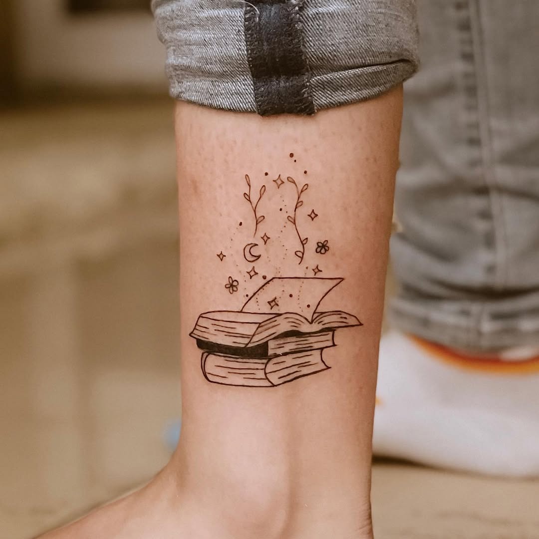 This ankle tattoo features an open book surrounded by delicate flowers and stars, embodying a sense of wonder and imagination.