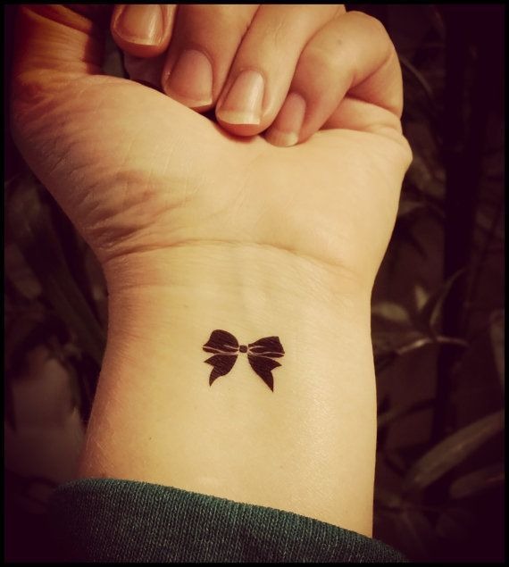 Tiny black bow tattoo on girl’s wrist Tattoo Design