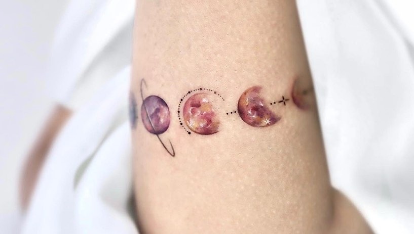This tattoo features a stunning bracelet design of moon phases with a galactic feel.