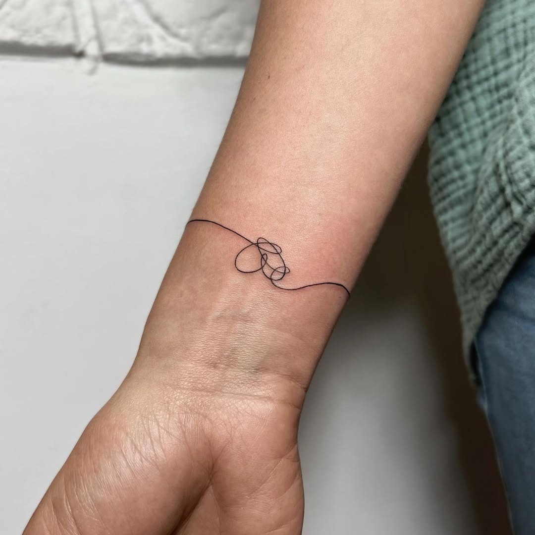 This tattoo showcases a delicate, minimalist design around the wrist.