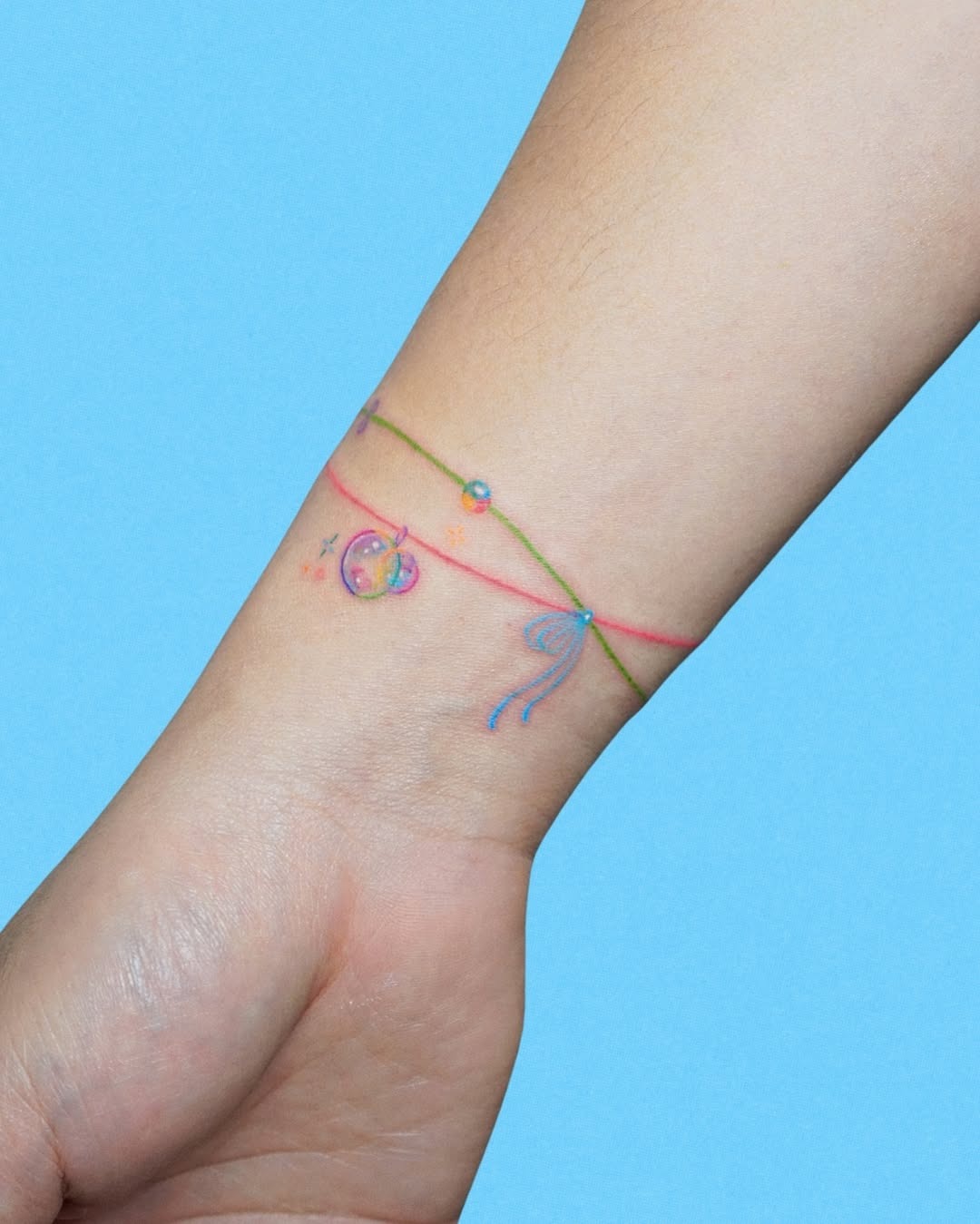 This bracelet tattoo features delicate swirls and playful charms, creating a whimsical look.
