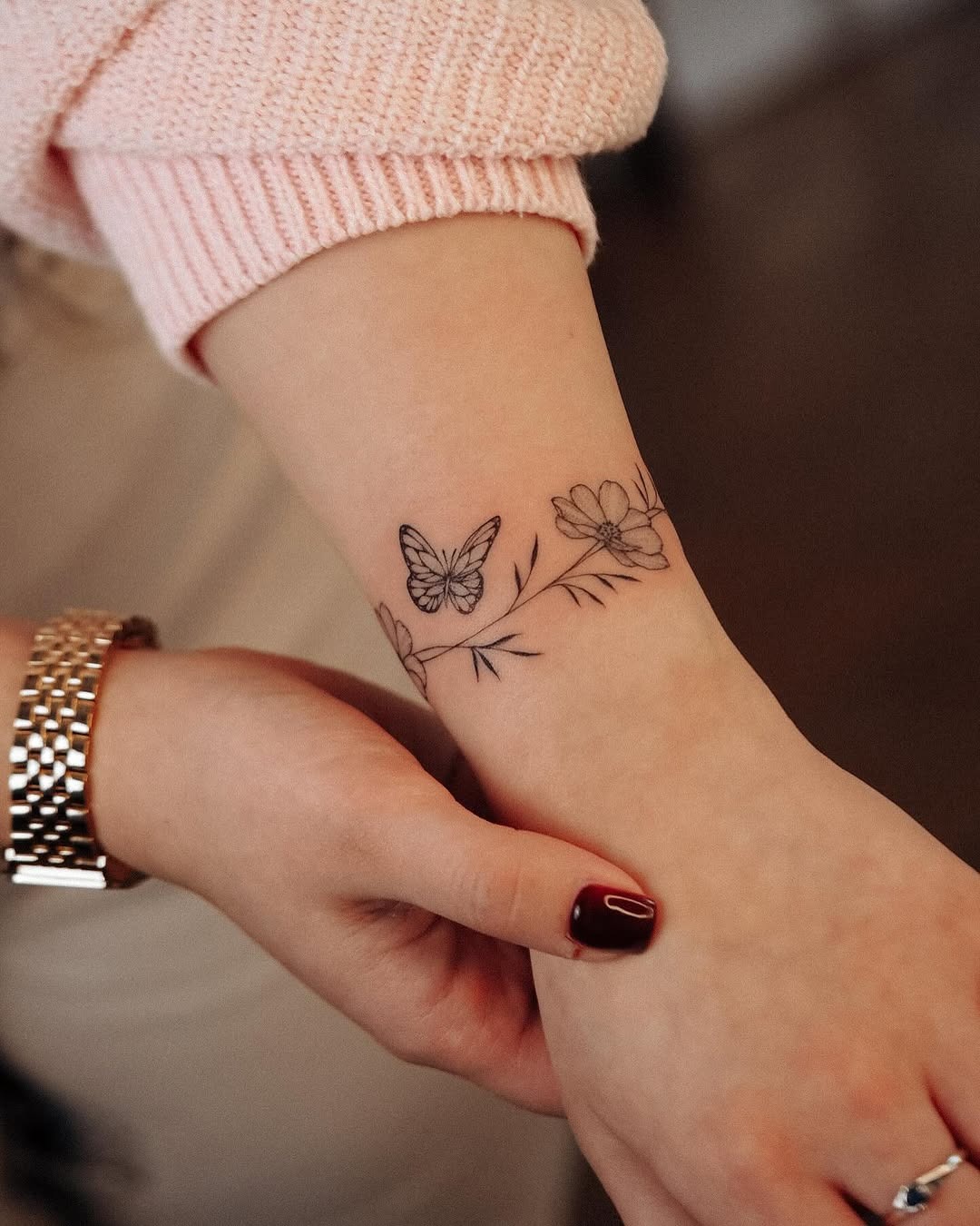 This tattoo features a beautiful butterfly alongside elegant flowers, wrapped around the wrist like a delicate bracelet.