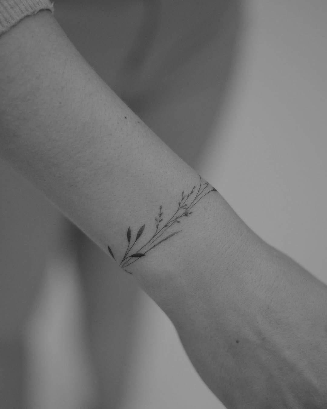 This tattoo features a soft floral pattern that wraps around the wrist, creating an elegant bracelet effect.