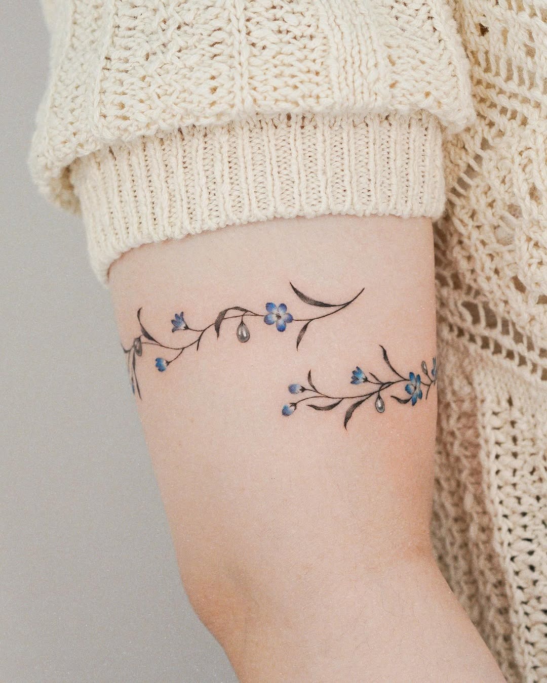 This tattoo features a beautiful floral design wrapping around the arm.