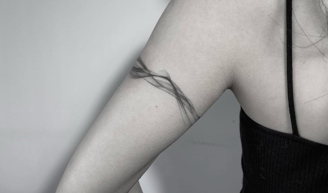 This tattoo features an elegant, abstract design that wraps around the arm.