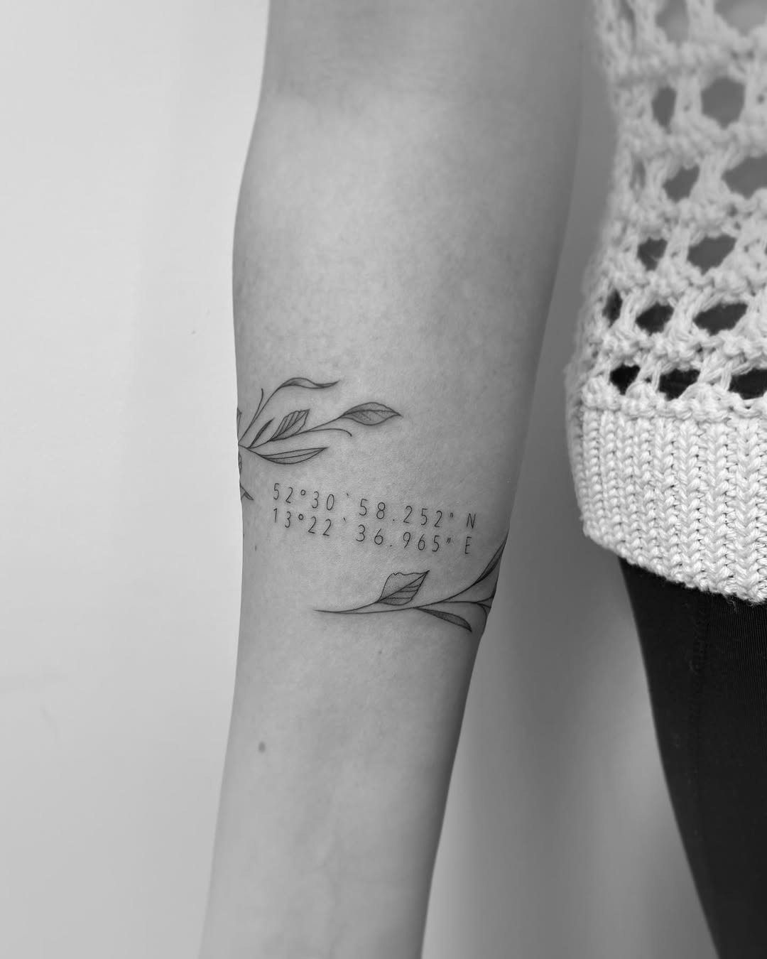 This tattoo beautifully combines natural elements with meaningful coordinates.