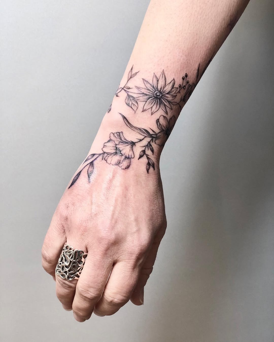 This captivating tattoo features intricate floral designs wrapping around the wrist.