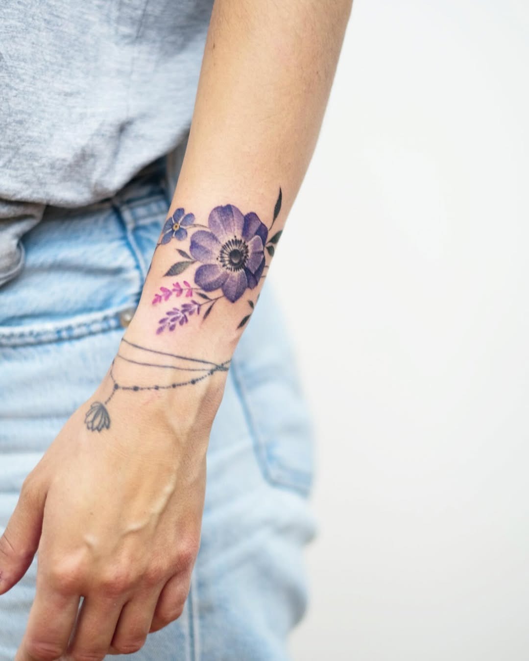 This captivating bracelet tattoo showcases an array of delicate flowers wrapped around the wrist.