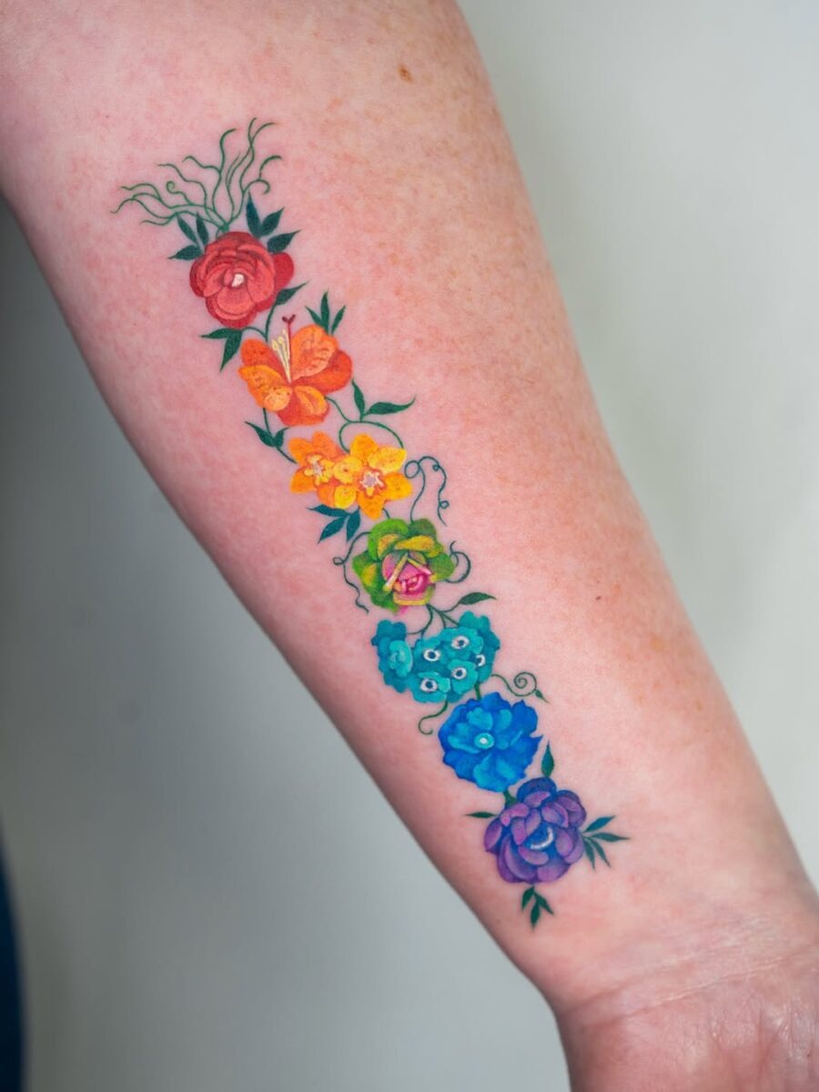 This tattoo showcases a stunning array of colorful flowers stretching along the arm.