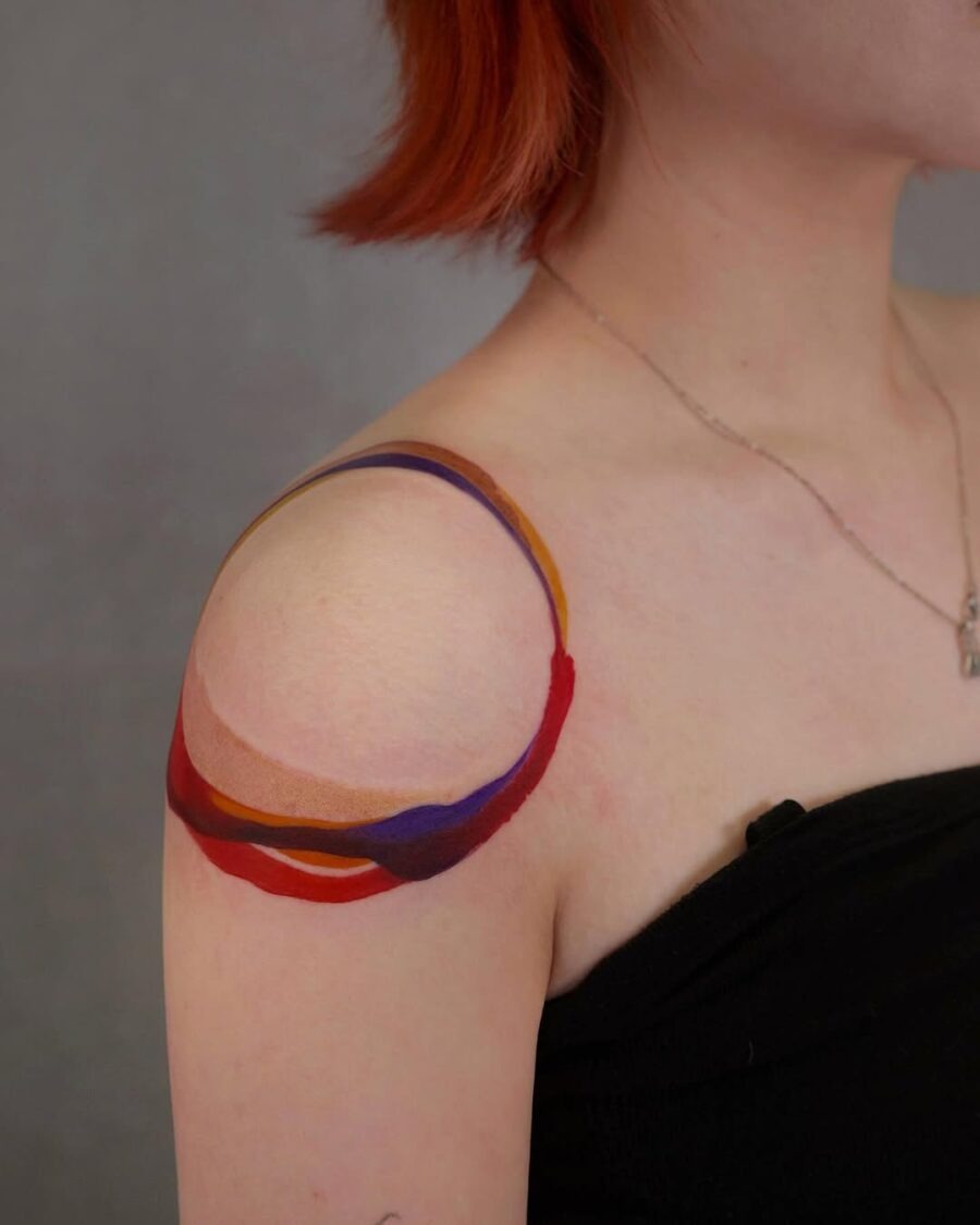 This bright color tattoo features bold, overlapping shapes on the shoulder.