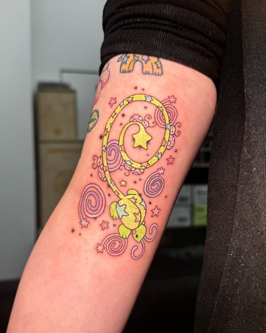 This bright color tattoo showcases a playful lizard entwined in swirling patterns.