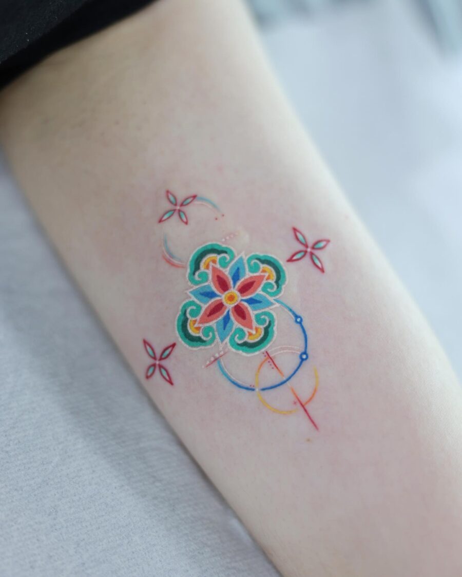 This bright color tattoo showcases a beautifully designed floral pattern, featuring a combination of aqua, red, and yellow hues.
