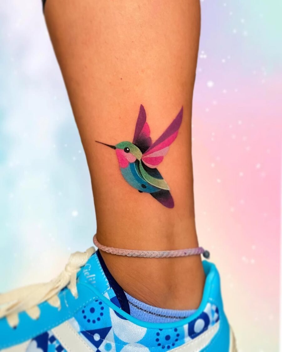 This tattoo features a stunning hummingbird, bursting with shades of pink, purple, and blue.