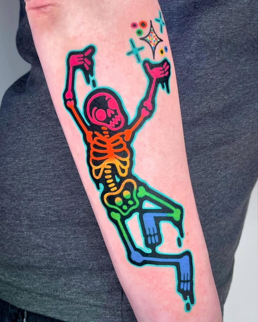 This tattoo features a colorful skeleton in a playful dancing pose.