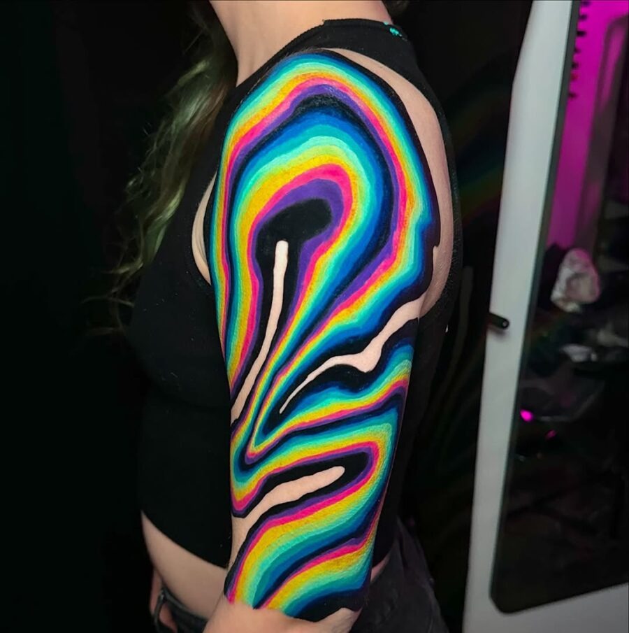 This colorful tattoo features a vivid blend of rainbow swirls that flow elegantly along the arm.