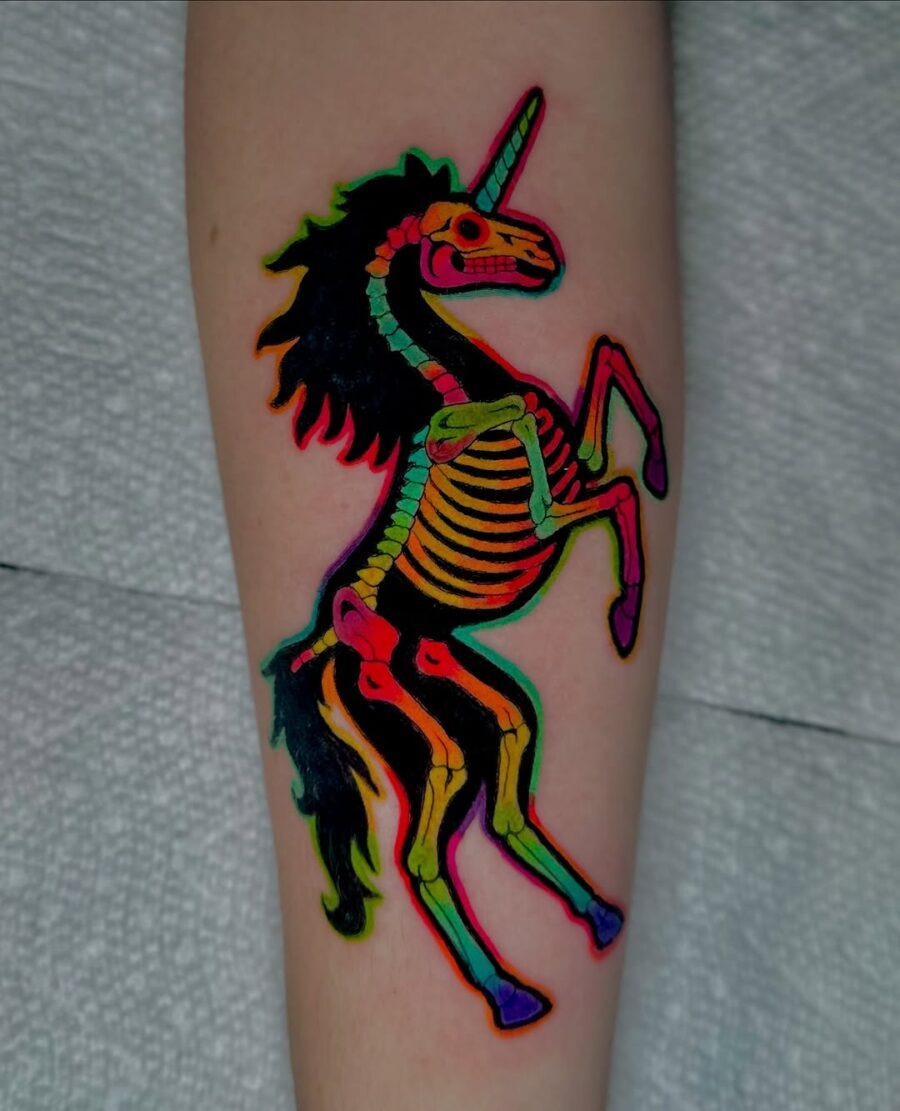 This unicorn skeleton tattoo bursts with colors, showing a playful and whimsical design.