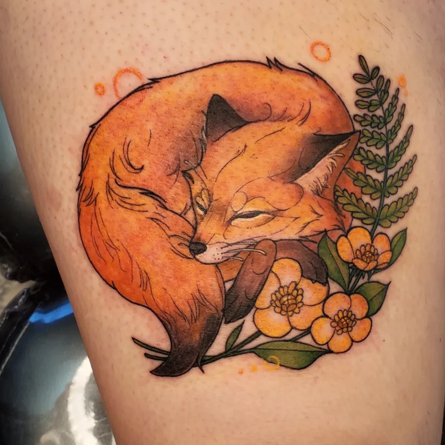 This tattoo features a whimsical fox curled up among buttercup flowers, creating a blend of wildlife and nature.