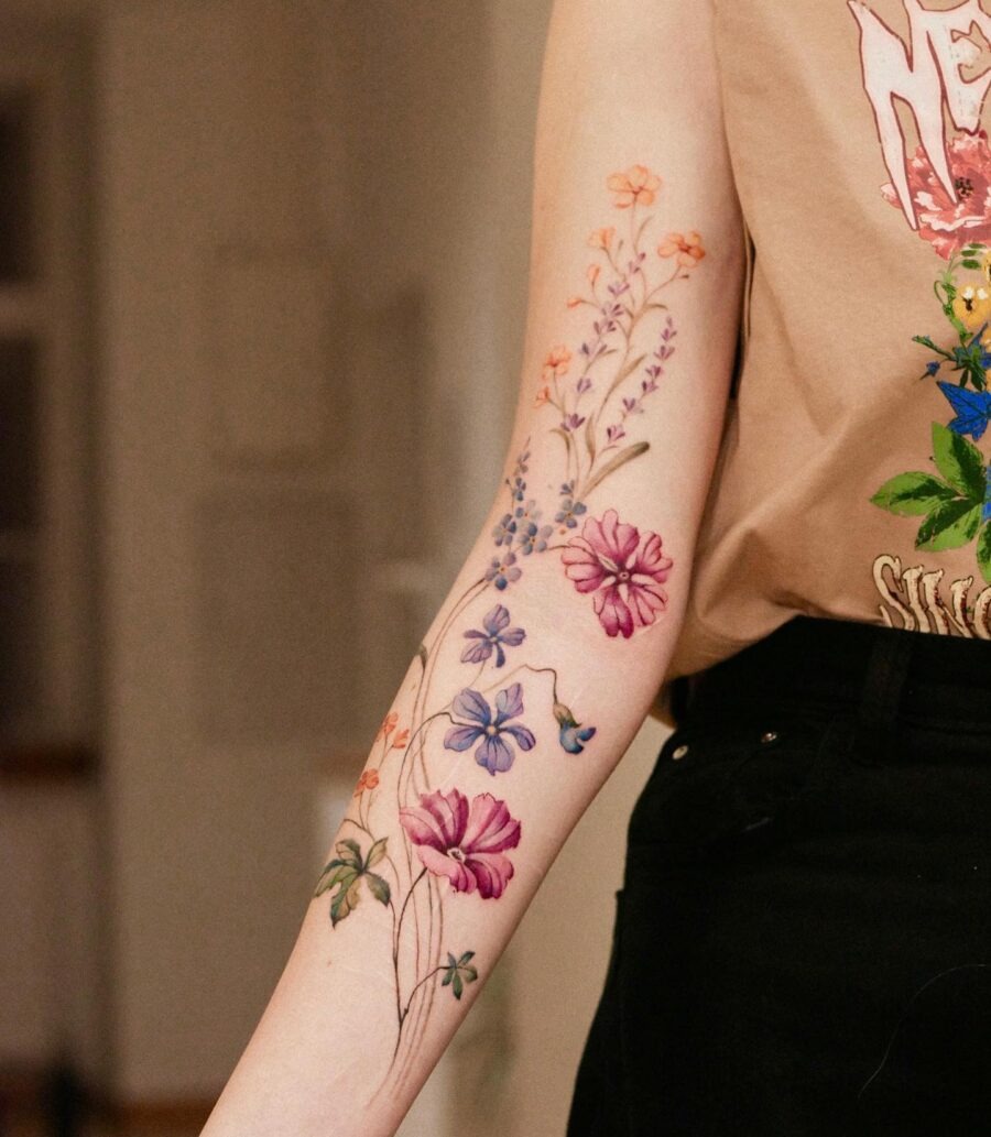 This tattoo features a collection of flowers, including delicate buttercups in various colors.