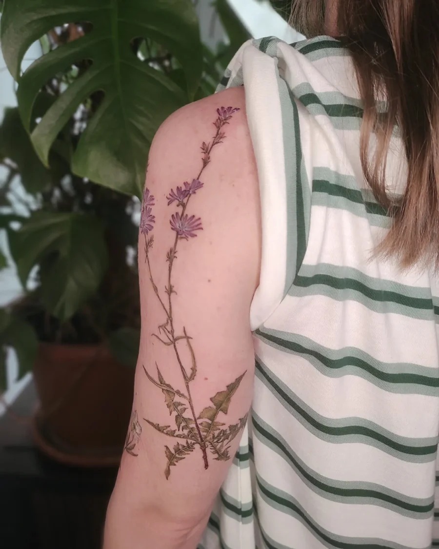 This tattoo features delicate buttercup flowers gracefully placed on the upper arm.