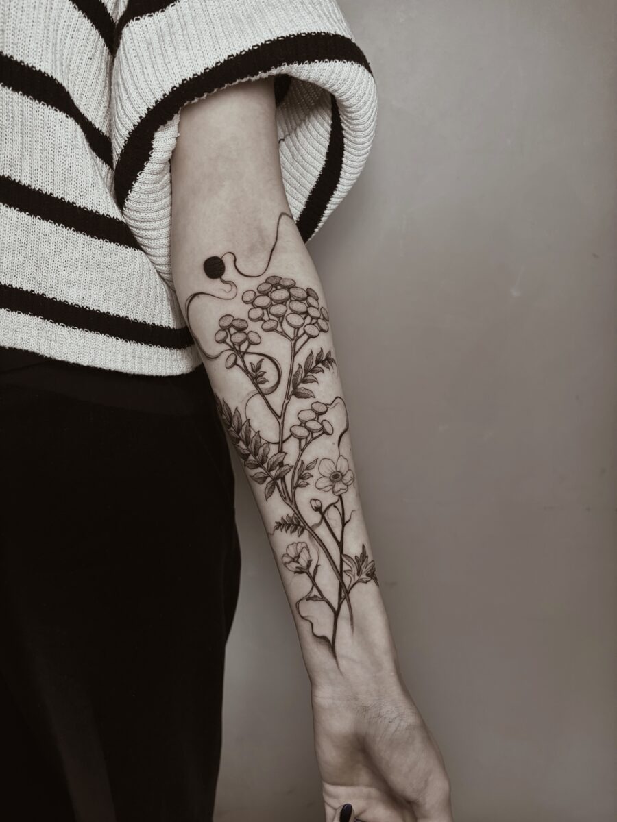 This buttercup flower tattoo features a delicate design that beautifully flows along the arm.