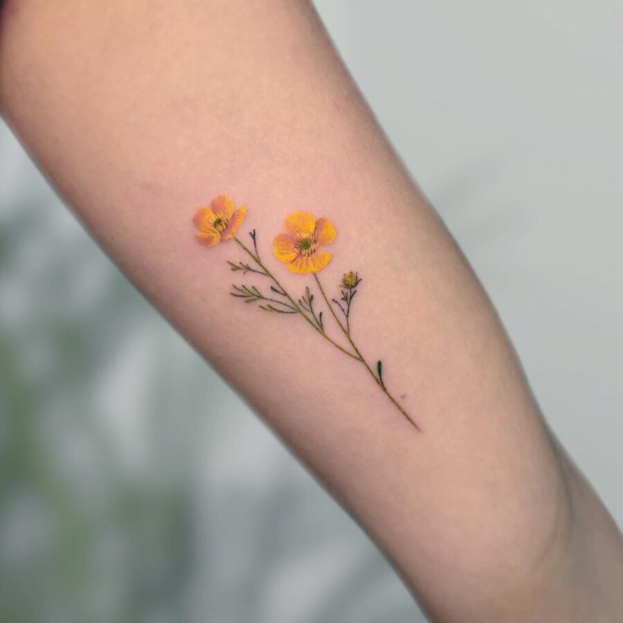 This tattoo features delicate yellow buttercup flowers with a slender stem, creating a charming and feminine design.
