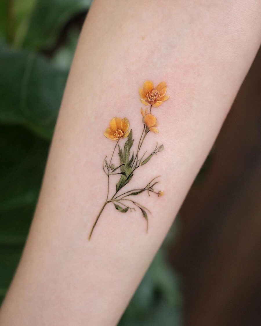 This delicate buttercup flower tattoo highlights warm orange hues and intricate details.