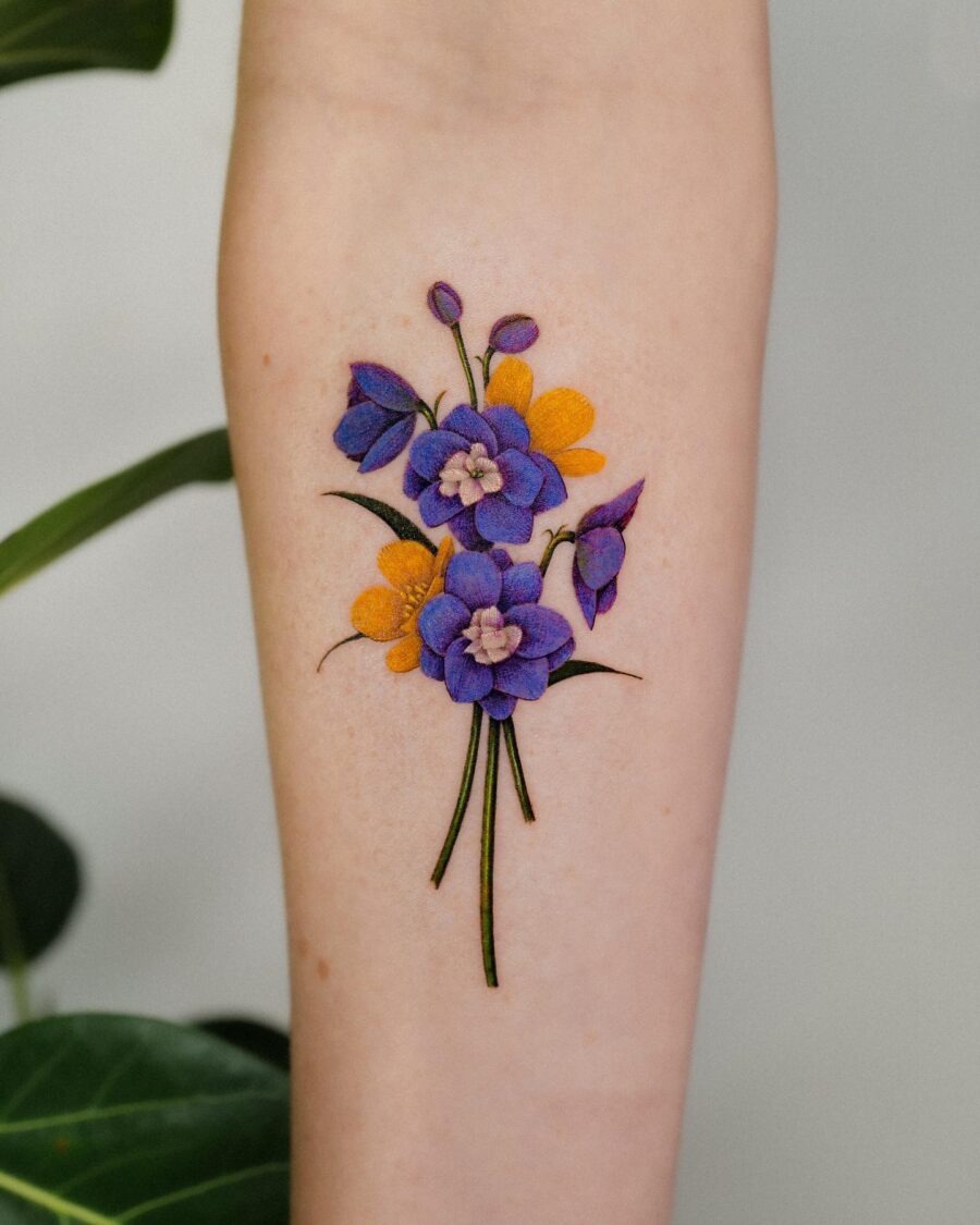 This tattoo features a stunning arrangement of buttercup flowers in a purple hue, contrasted with cheerful yellow blossoms.