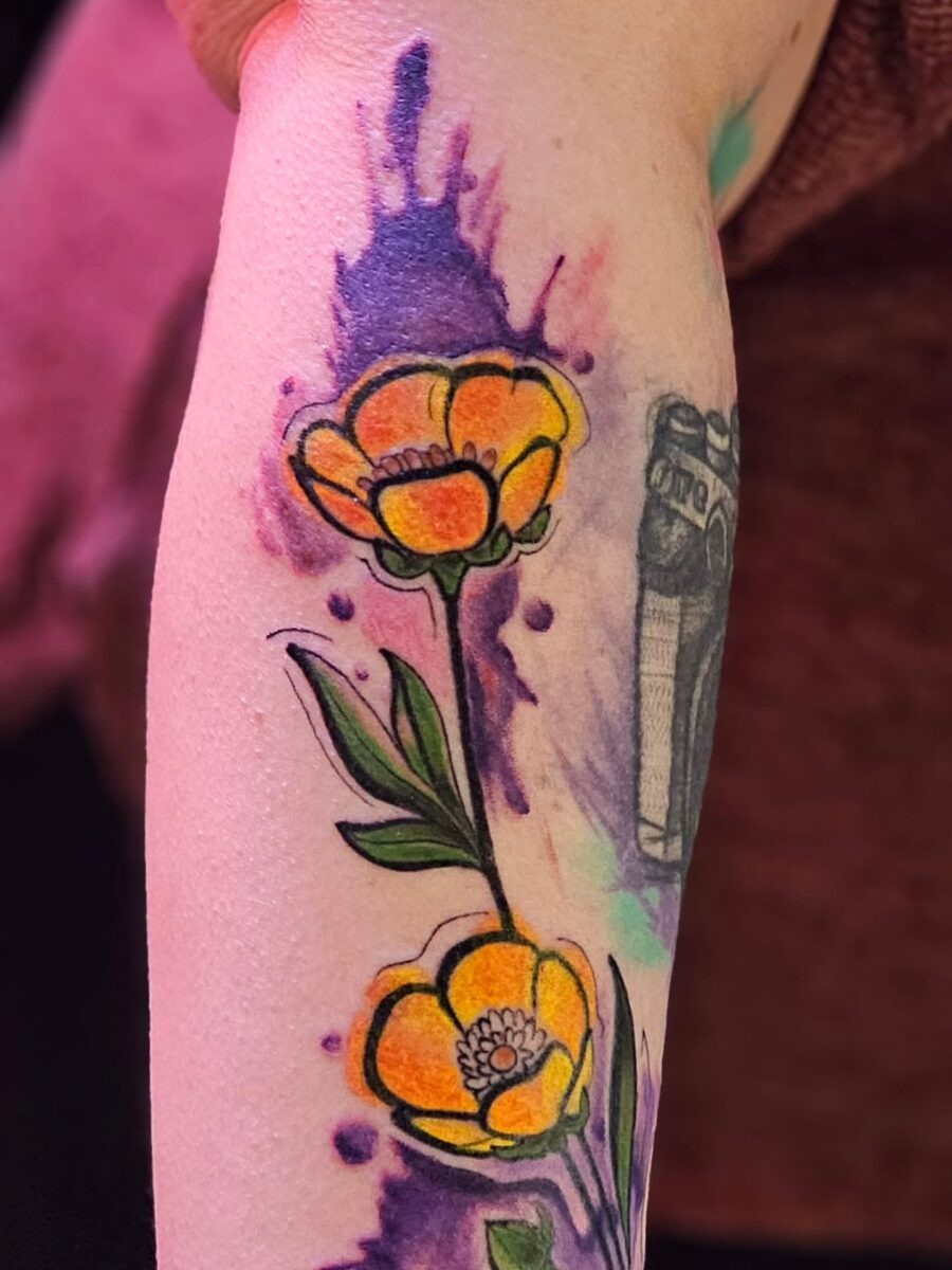 This tattoo features buttercup flowers beautifully intertwined with bold green leaves.