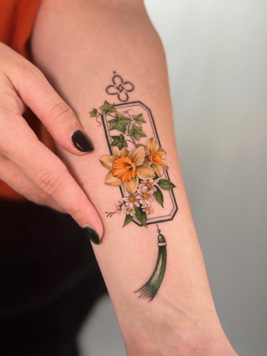 This tattoo features a striking blend of buttercups and lush greenery, surrounded by delicate floral accents.