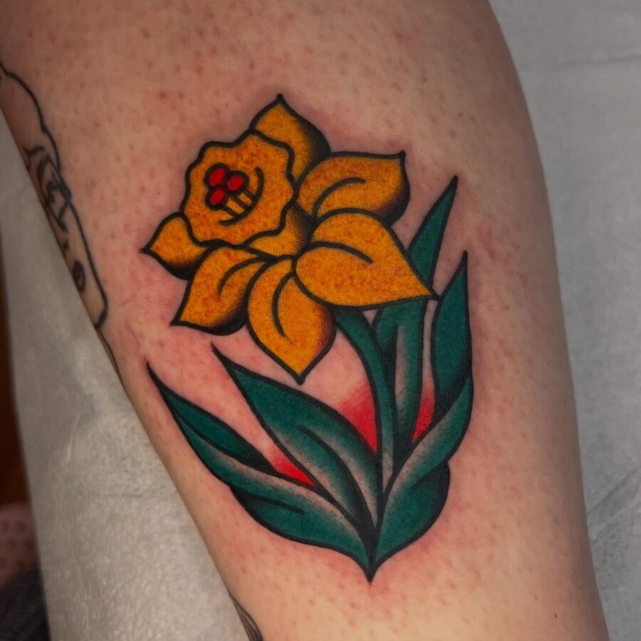 This striking buttercup flower tattoo features vivid yellow petals that stand out beautifully against rich green leaves.