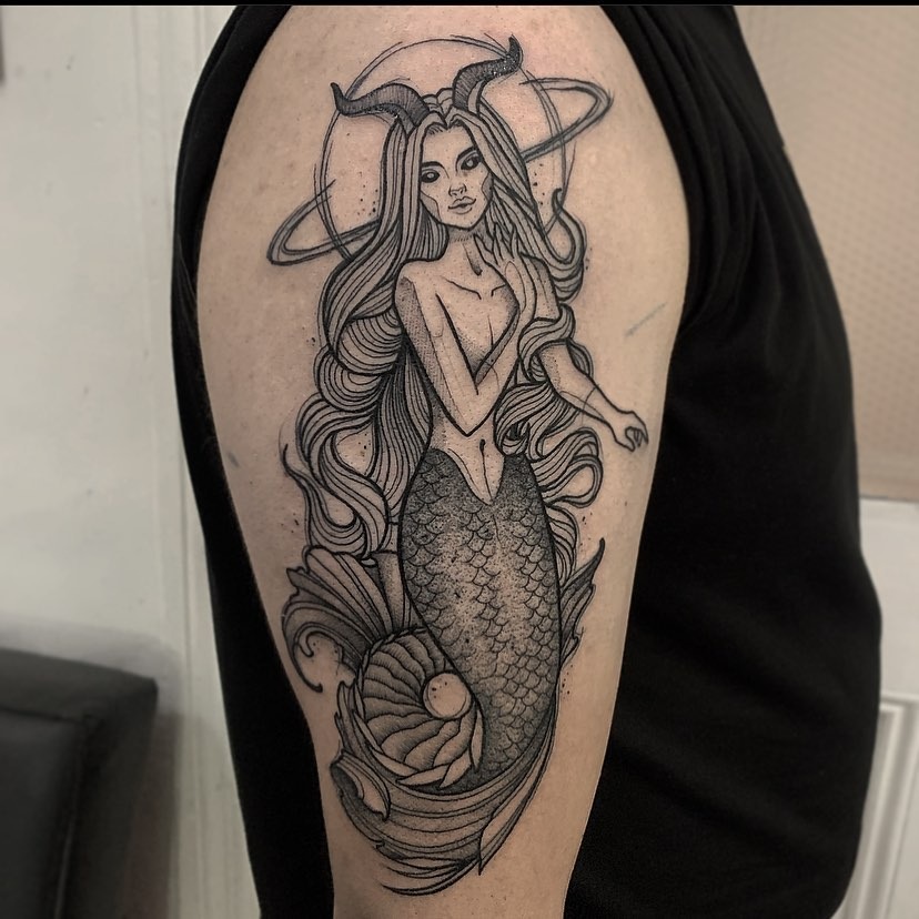 This stunning tattoo features a mermaid representing Capricorn, adorned with flowing hair and an intricate tail.