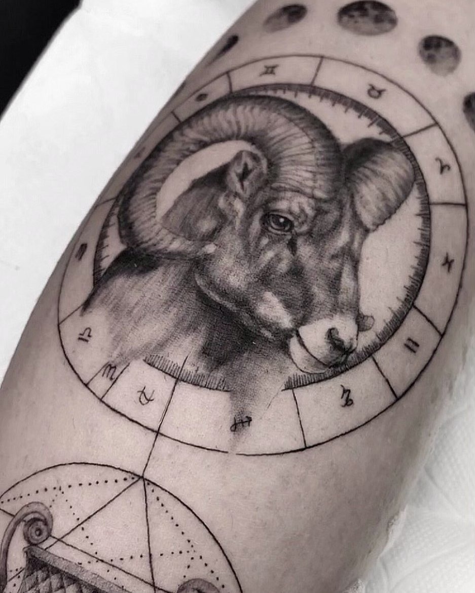 This striking Capricorn tattoo features a detailed ram head, surrounded by zodiac symbols.