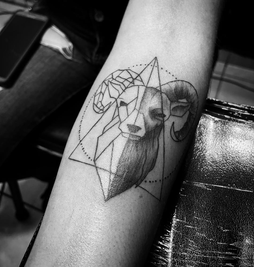 This tattoo features a sleek representation of a ram with intricate geometric shapes.