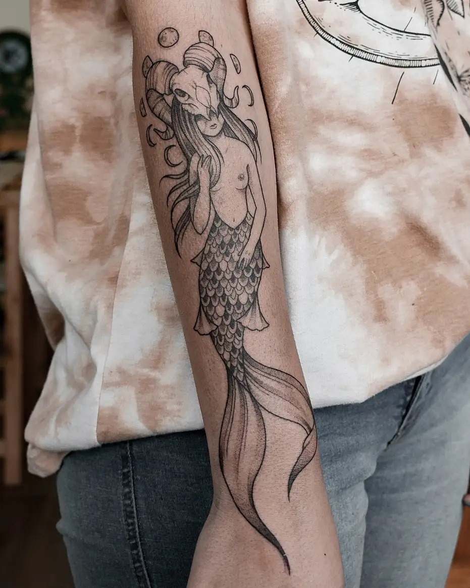 This striking tattoo blends the Capricorn symbol with mermaid elements, showing a smooth fusion of two motifs.