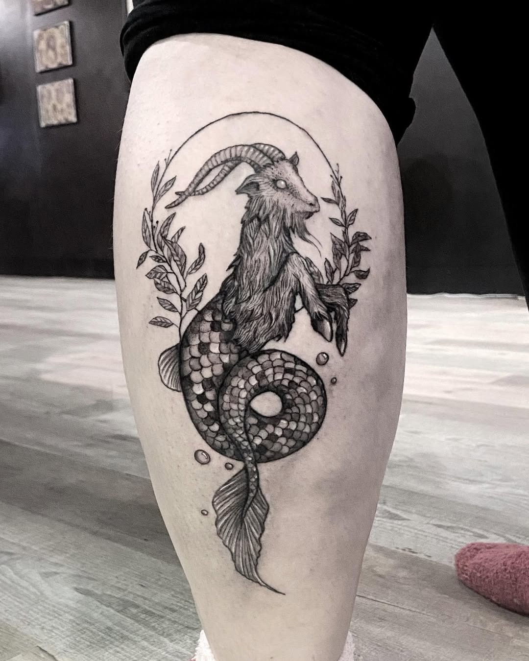 This captivating tattoo features a stylized Capricorn merging with a mermaid, surrounded by beautiful foliage.
