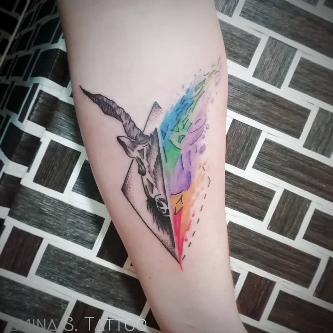 This Capricorn tattoo combines celestial imagery with a stunning rainbow effect.