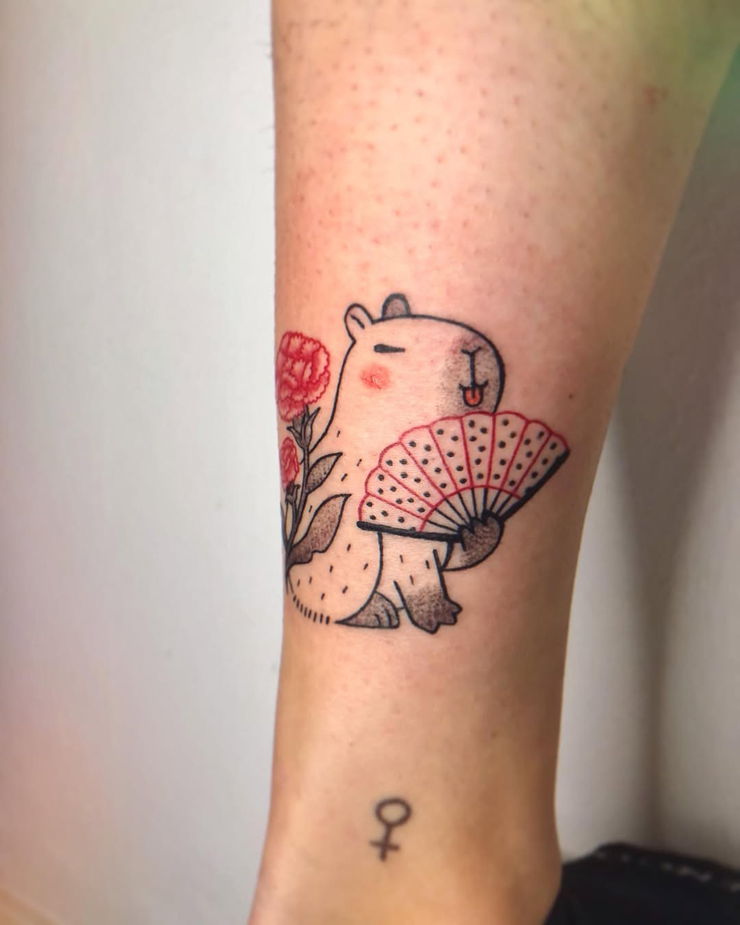 Charming capybara holding a fan and flowers Tattoo Design