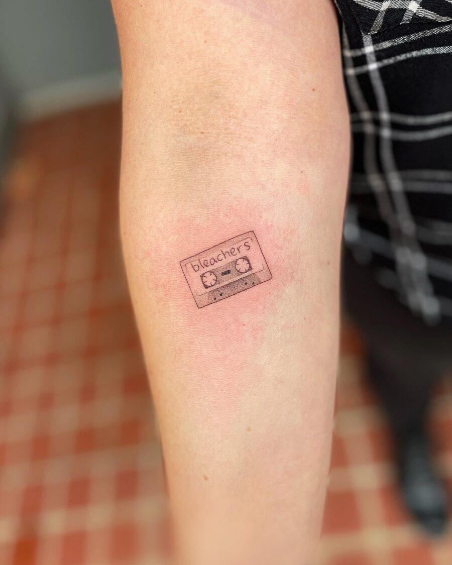 This tattoo features a vintage cassette tape design, subtly inked on the forearm.