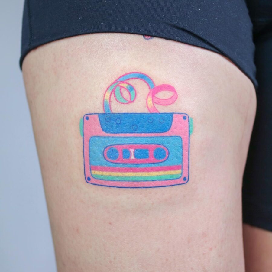 This tattoo showcases a retro cassette tape, bursting with color.