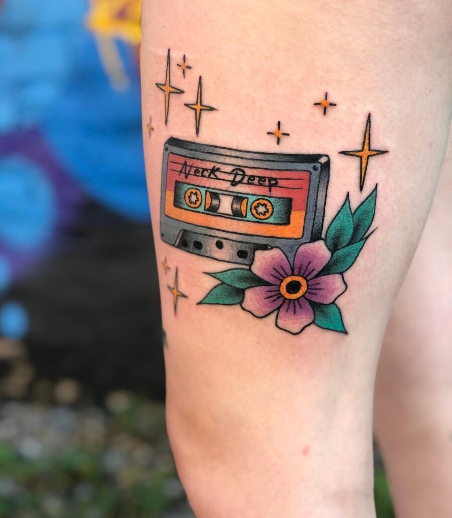 This tattoo features a cassette tape surrounded by stars and a blooming flower.
