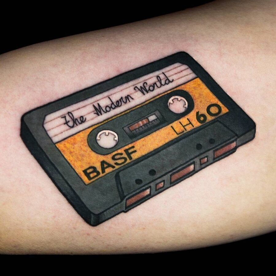 This tattoo features a detailed illustration of a vintage cassette tape, beautifully inked on the skin.
